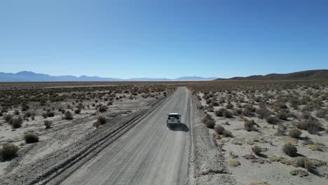 Aerial-of-a-car-traveling-in-the-wild-Andes-mountain-terrain,-Deserted-landscape,-Argentina