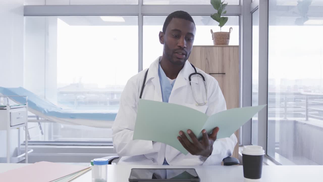 African american male doctor making video call in hospital, slow motion
