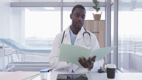 african american male doctor making video call in hospital, slow motion