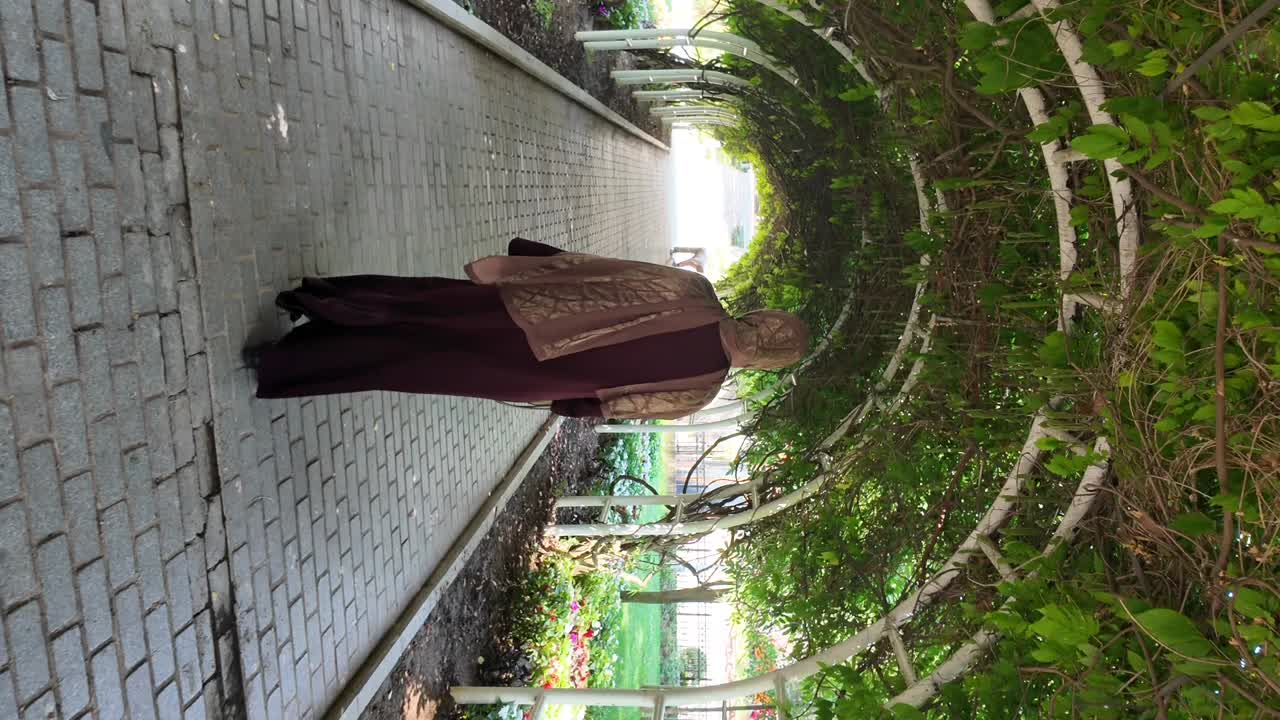 A person walking under a lush green archway in a park