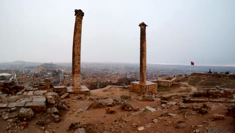 dos columnas del castillo de urfa en el fondo ciudad y bandera roja turca en el viento nieve y lluvia