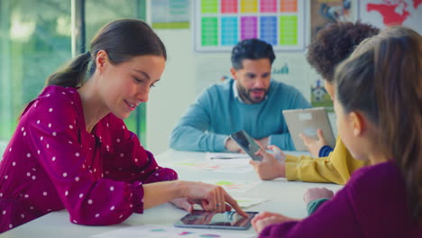 Elementary-School-Students-And-Female-Teacher-Using-Digital-Tablets-In-Classroom-Lesson