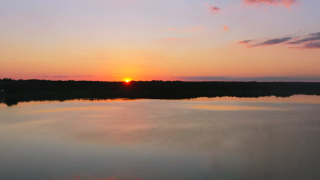 aerial-of-beautiful-fire-red-sunset-setting-below-horizon-surrounded-by-tropical-water-at-Laguna-Coba-town-in-Mexico-with-purple-sky