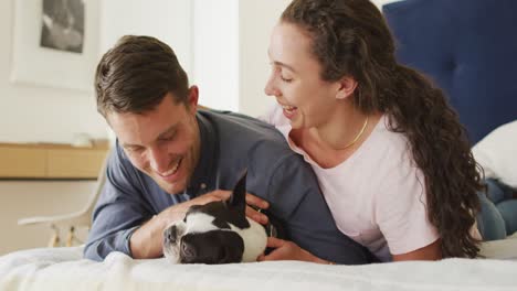 Caucasian-couple-playing-with-dog-in-bad-at-home