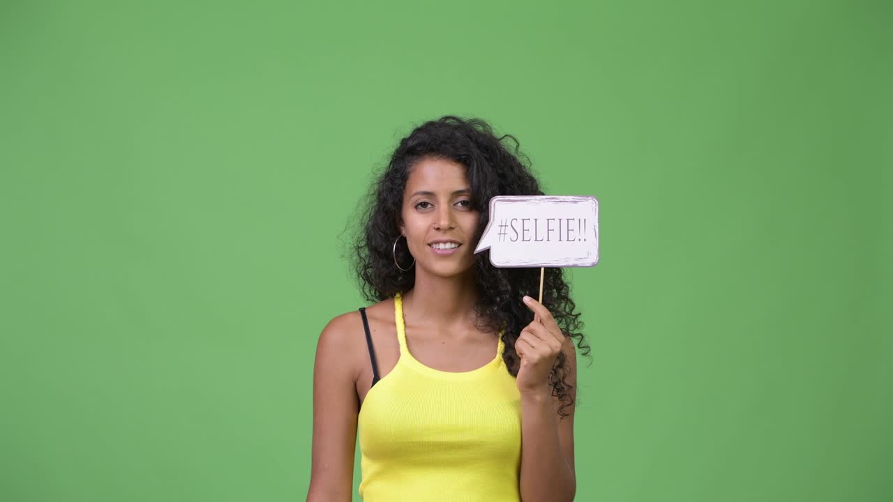 Giovane e bella donna ispanica con un cartello di carta per selfie.
