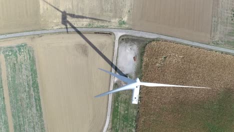 high aerial drone shot of windmill in between farmland with shadow