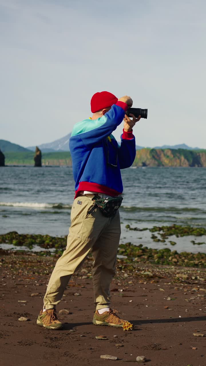Man Photographing Scenic Ocean Landscape with Camera on Beach
