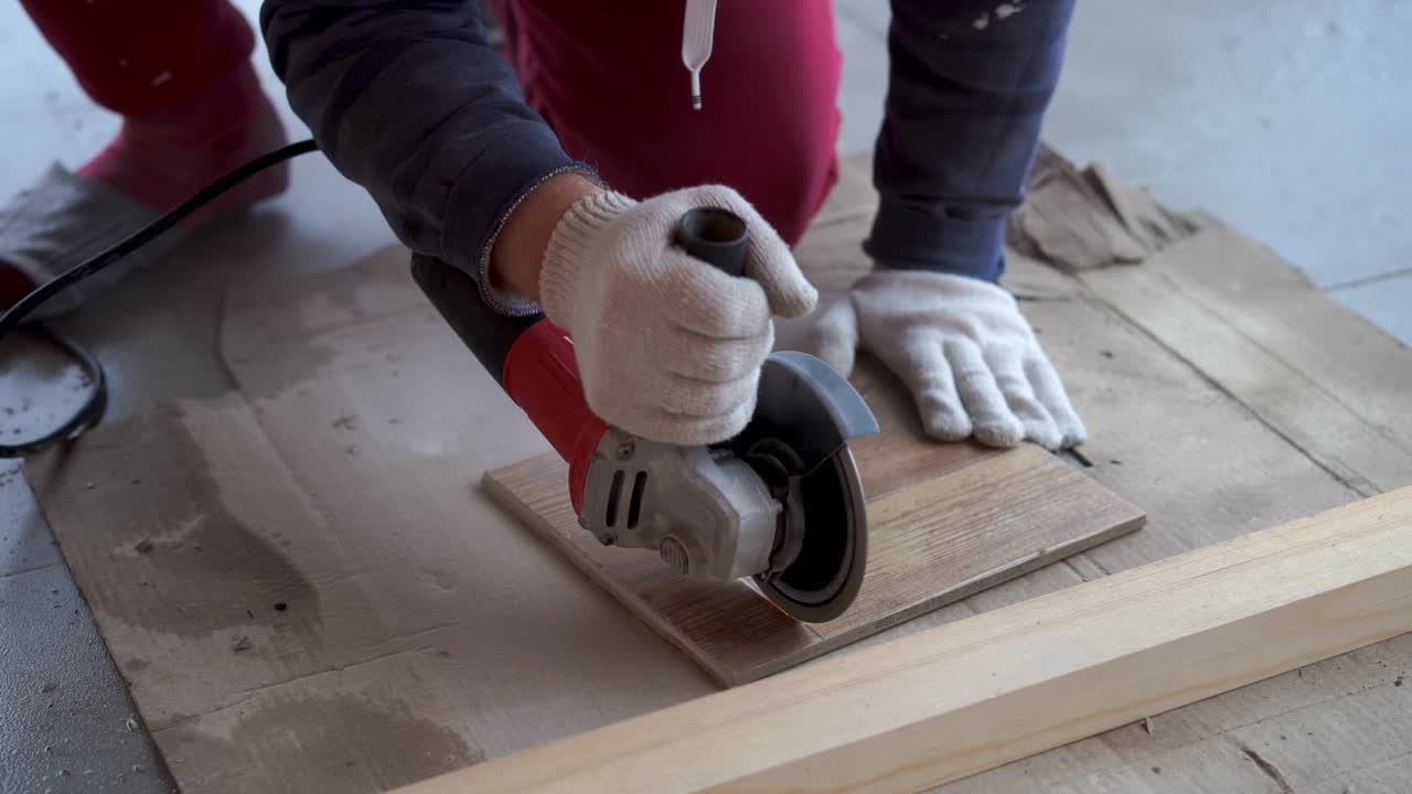 reparación y decoración. un hombre corta azulejos de cerámica con un molinillo.
