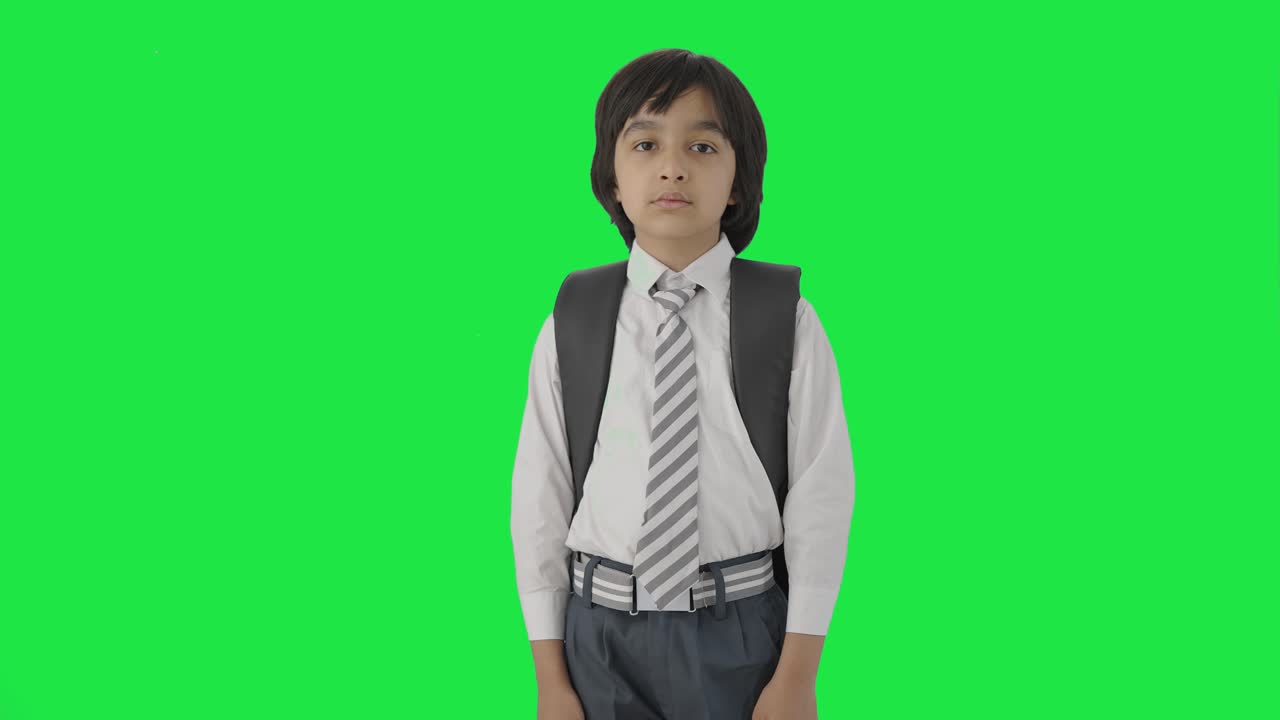 niño de escuela indio serio mirando la cámara pantalla verde