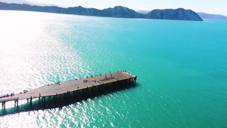 muelle largo en la bahía de tolaga, foto aérea de personas disfrutando de un paseo durante un día soleado