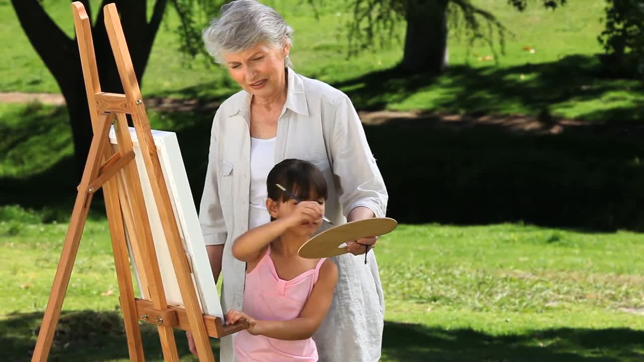 una chica bonita pintando un lienzo con su abuela