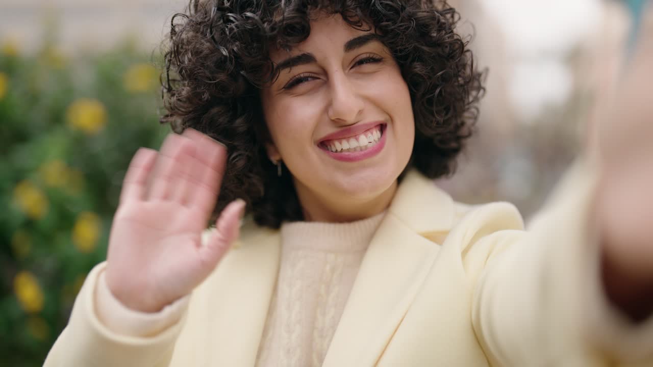 una mujer joven sonriendo confiada haciendo una llamada de video en el parque.