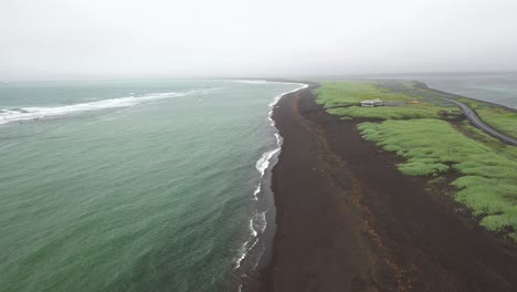 Schwarzer-Sandstrand-In-Island-Mit-Grünem-Gras-Und-Drohnenvideo,-Das-Sich-Nach-Unten-Bewegt