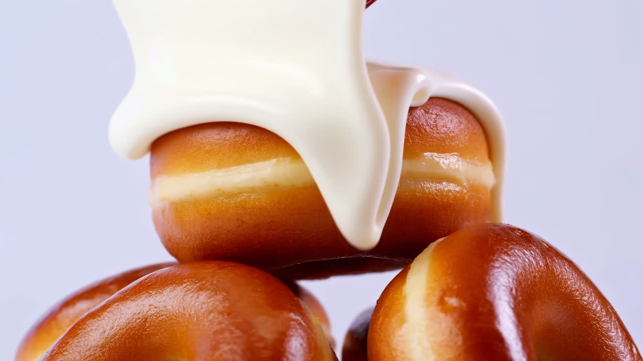 Glazed Donuts Stacked With Vanilla Cream Pouring Slowly Over Warm Golden Pastries, Glossy Surface Catching