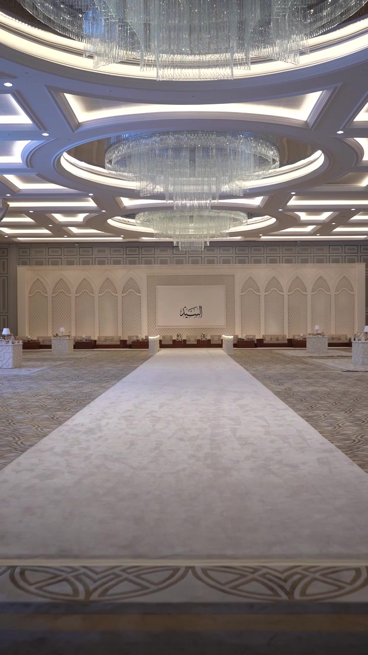 Vista attraverso un arco ornato in una lussuosa sala da ballo araba caratterizzata da un lungo tappeto bianco e splendidi lampadari di cristallo