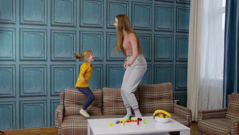 Happy-funny-family-mother-and-child-kid-daughter-dancing,-jumping-on-sofa,-listening-music-at-home