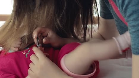 madre joven corta las uñas de su bebé bonito