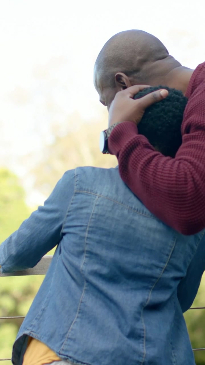 Video verticale: Papà che si avvicina mettendo una mano sul bambino, confortandolo vicino alla ringhiera, con giacca di jeans visibile.
