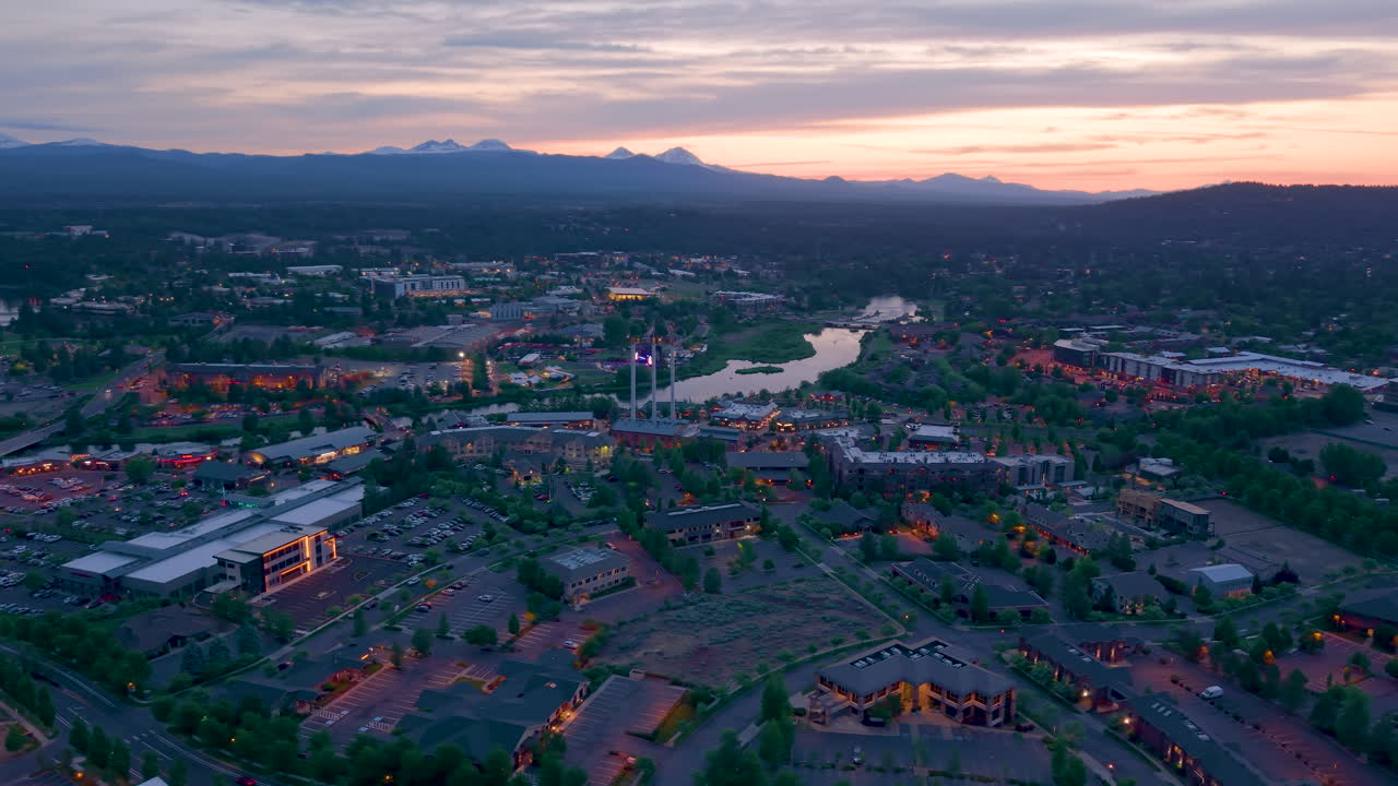 Sunset over the mountains and city of Bend Oregon. Drone flight over of the old mill district during evening.