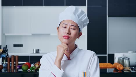 アジアの女性シェフが何かについて考え自宅のキッチンを見回しています