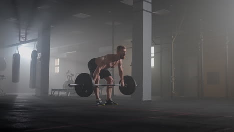 slow motion: brutal athlete lifts the bar above himself performing a jerk a spinning push. a man is engaged in weightlifting on a dark background portrait. concept strength power playing sports.