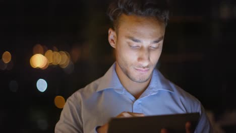 Fokussierter-Birazialer-Geschäftsmann,-Der-Nachts-Im-Büro-Ein-Tablet-Nutzt,-Zeitlupe