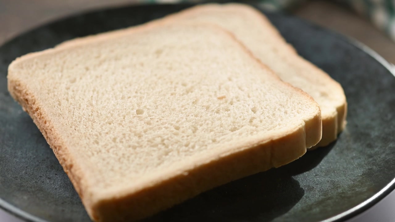 Two Slices of White Bread on a Dark Plate