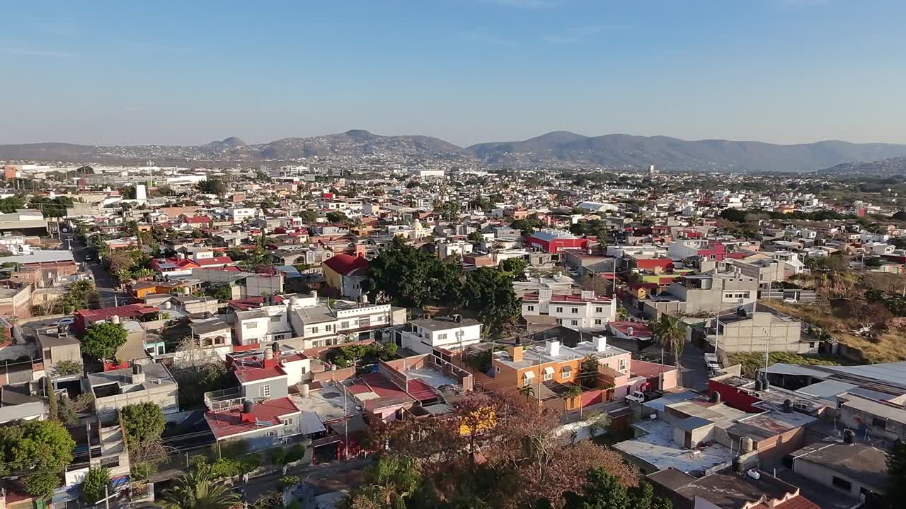 Vista aerea che cattura le case colorate di Jiutepec, Morelos, Messico, con uno sfondo di maestose montagne sotto un cielo azzurro e limpido, mettendo in mostra il paesaggio urbano e la bellezza naturale della regione