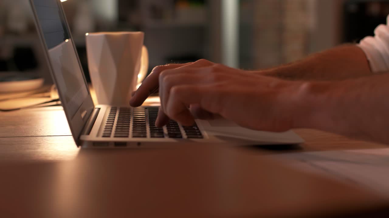 Side view of human hands typing on laptop
