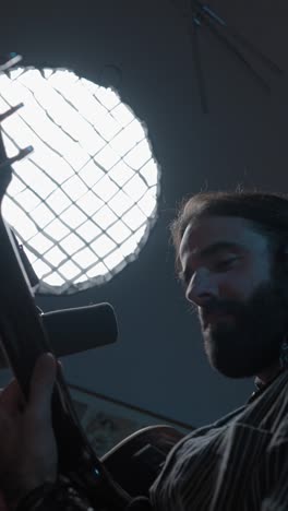 musician singing and playing guitar in a studio with a large light source