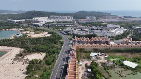 aerial video reveals a newly built town showcasing a distinct architectural style with colorful buildings tightly lining developed with wide roads and some surrounding green spaces. a range of hills
