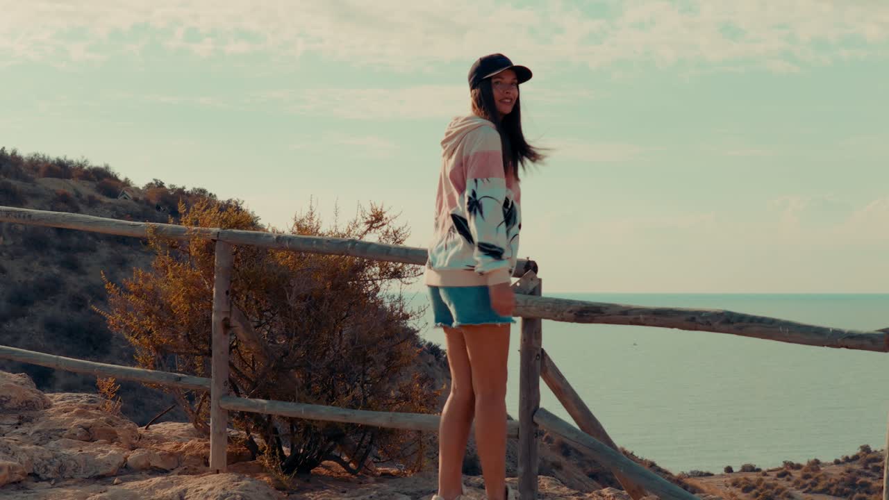 Happy woman looking at the sea from a viewpoint located on the top of a mountain