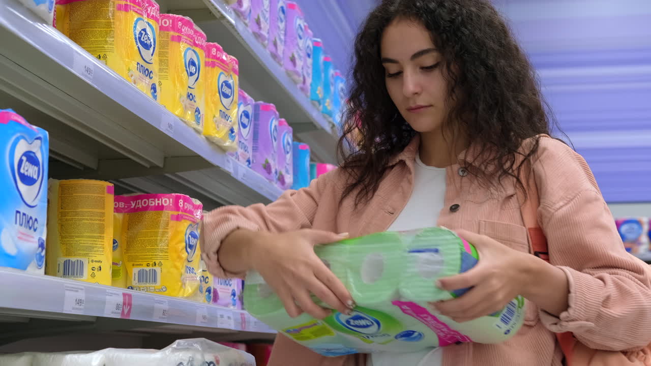 mujer comprando toallas de papel en una tienda de comestibles