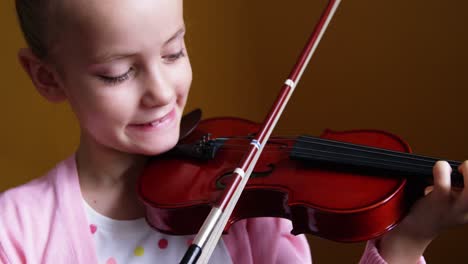 schoolgirl playing violin in classroom at school