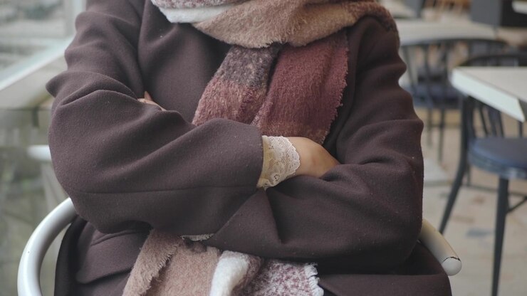 Donna seduta con le braccia incrociate in un caffè