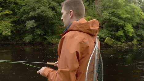 Hand-held-shot-of-a-fly-fisherman-casting-his-line-and-lures-into-a-river