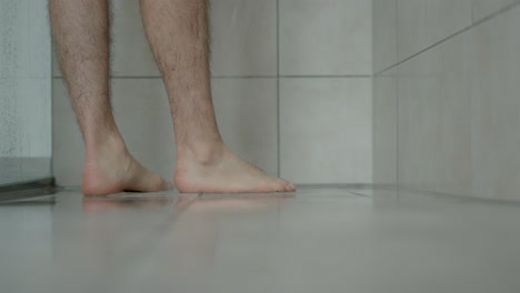 man-runs-into-shower-close-up-on-legs