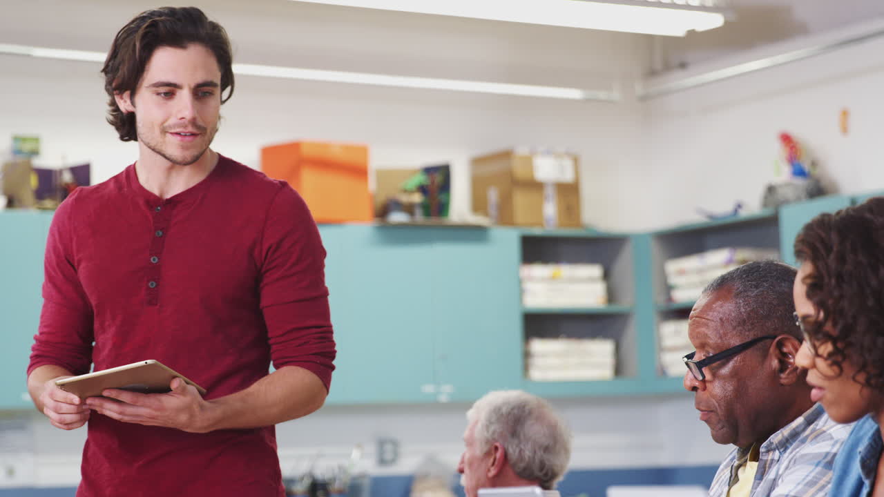 maestro que ayuda a los estudiantes maduros que asisten a la clase en el centro comunitario