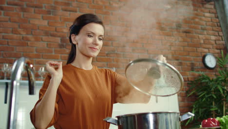 woman cooking healthy food in kitchen. girl salting hot meal in boiling pot.