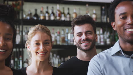 Retrato-De-Un-Hombre-Sonriente,-Propietario-Del-Bar-Del-Restaurante,-Con-Un-Equipo-De-Camareros-De-Pie-Junto-Al-Mostrador