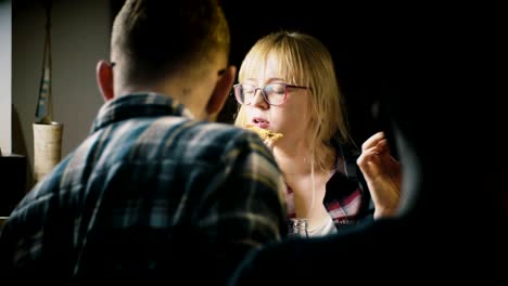 young beautiful european girl in glasses enjoys eating pizza and talking at a casual house party with friends