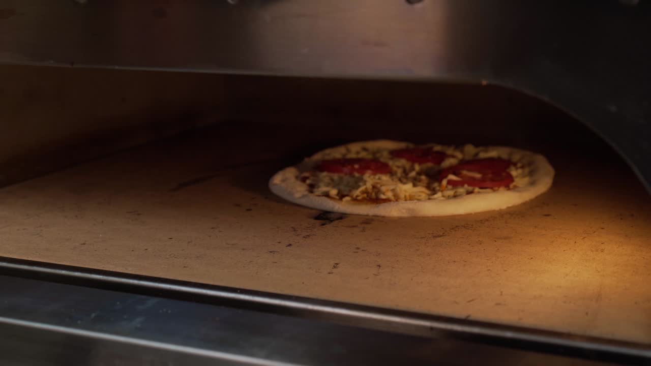 Kokk skjærer nybakt pizza med rund pizzakutter