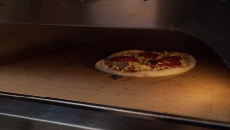 chef cuts freshly made pizza with round cutter