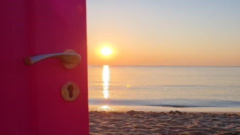 View-through-an-open-door-to-the-ocean-and-sandy-beach-at-sunrise-1