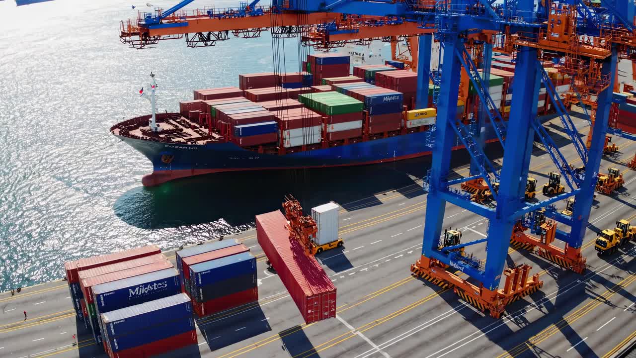 Aerial view of a bustling port with cranes unloading a cargo ship