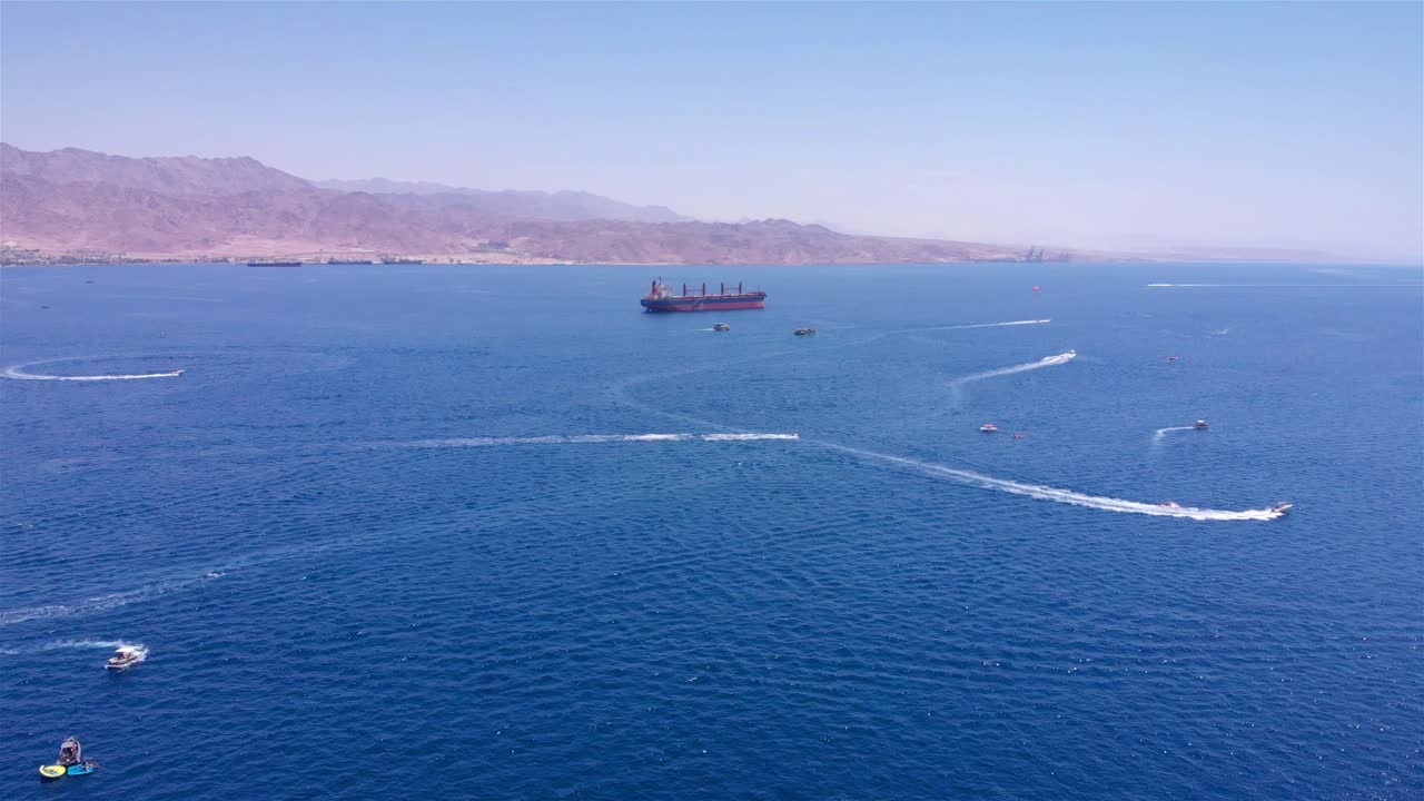 Aerial view of a busy bay with recreational boats and a large cargo ship