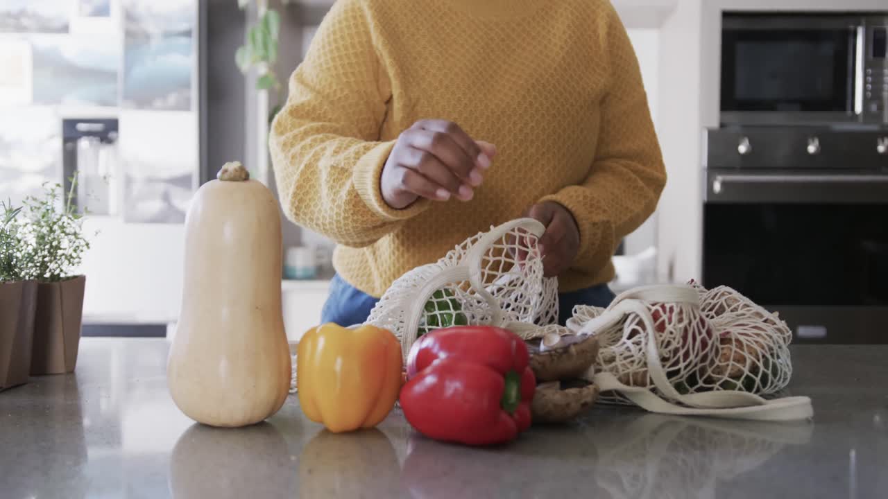 슬로우 모션으로 부 ⁇ 에서 식료품을 풀고 있는 아프리카계 미국인 여성의 중간 부분