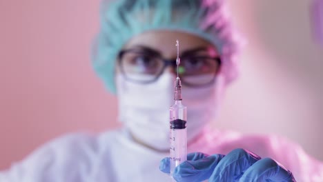 close up focused injection needle holding by hands with gloves of unfocused nurse wearing mask for protection by coronavirus