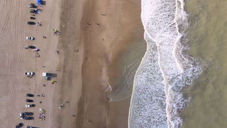 toma estática de un avión no tripulado de arriba hacia abajo de una playa en cariló, argentina con olas que se estrellan en la orilla