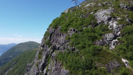 Vía-Ferrata-Ruta-De-Senderismo-A-Lo-Largo-Del-Borde-De-Cliff-Hoven---Incluida-La-Vista-Del-Popular-Y-Arriesgado-Lugar-De-Salto-De-Base---Antena-En-Movimiento-Ascendente-Contra-La-Cima-De-La-Montaña-Hoven-Y-Loen-Skylift---Nordfjord-Noruega